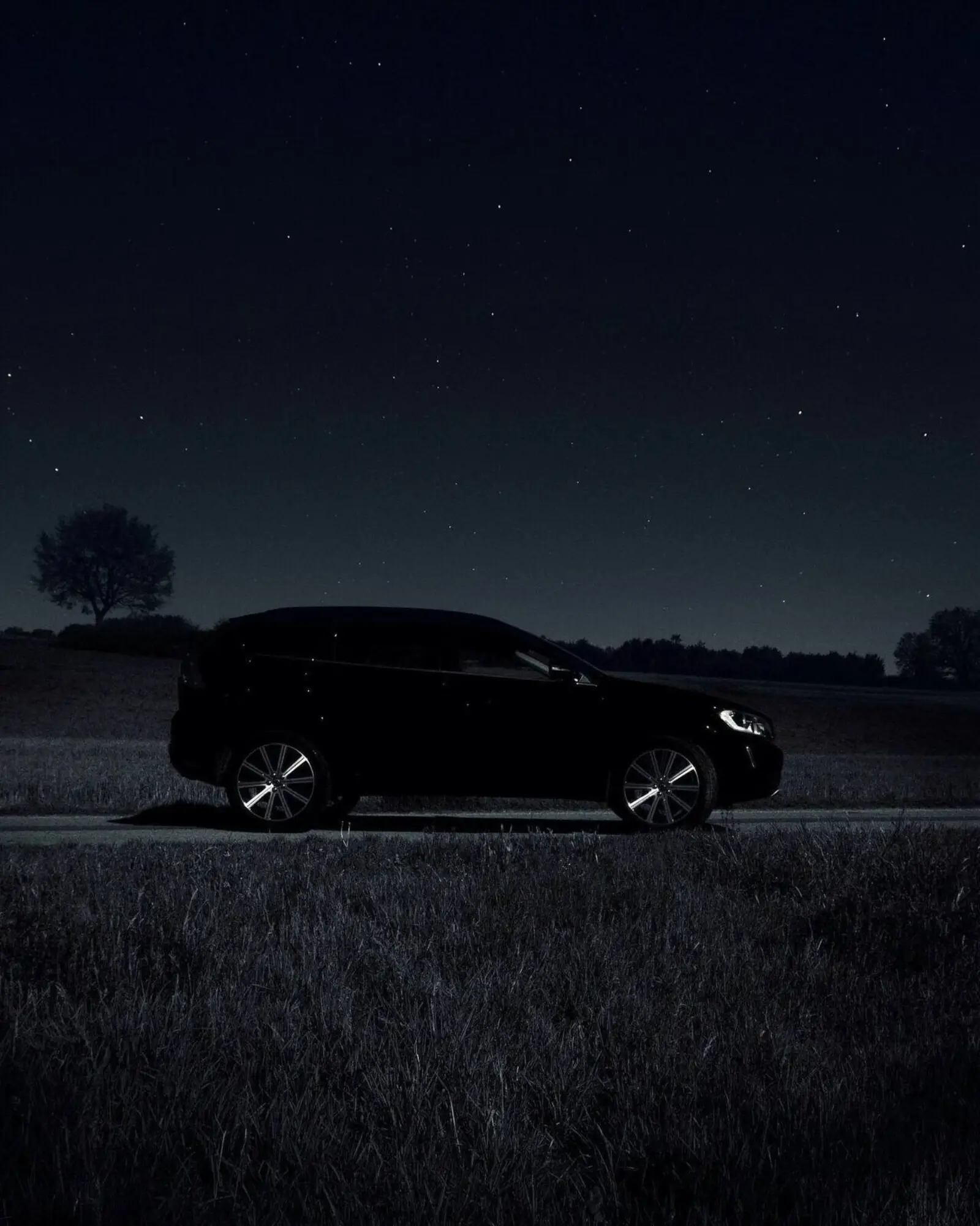 Black sedan at a porte cochere arrival under sodium light at night