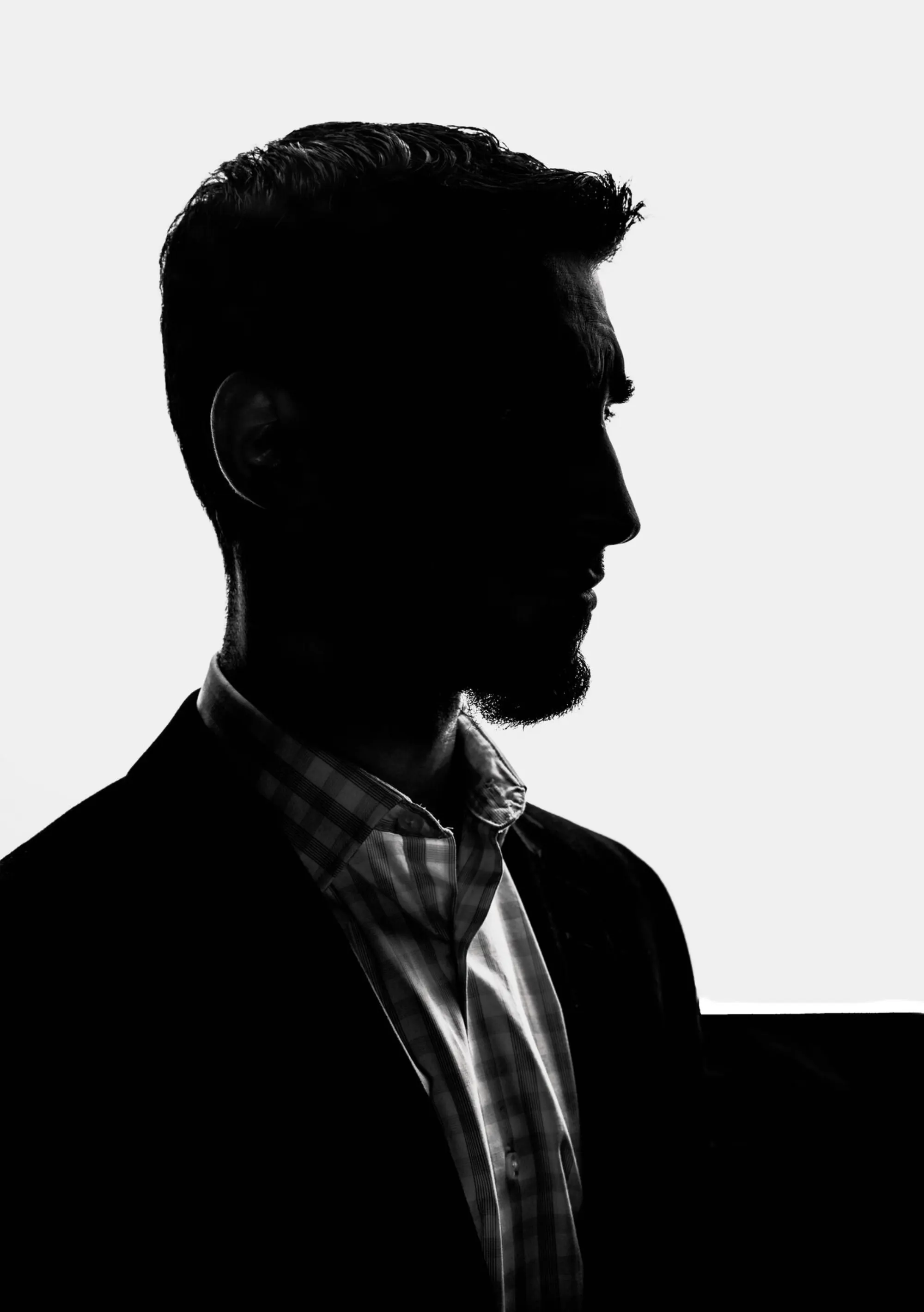 Suited operator standing in low light, plain-clothes posture, placeholder