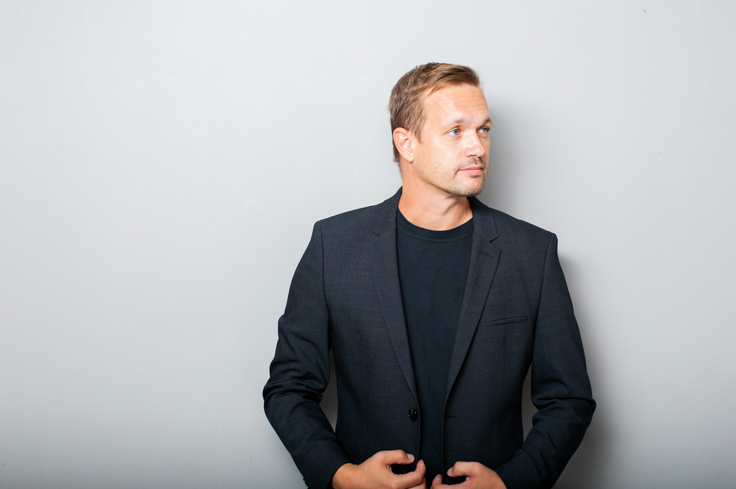 Suited operator, plain-clothes posture, low-key portrait